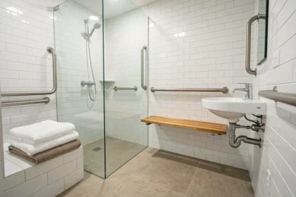 Salle de bains rénovée et accessible avec douche à l'italienne, barres d'appui et lavabo adapté en fauteuil roulant